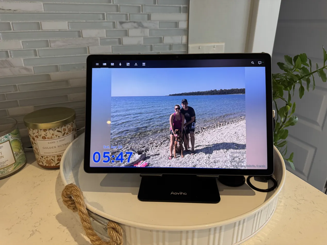 The kitchen tablet on the Aoviho stand, showing the Synology Immich photo view, which is the default screensaver when the dashboard isn't in active use.